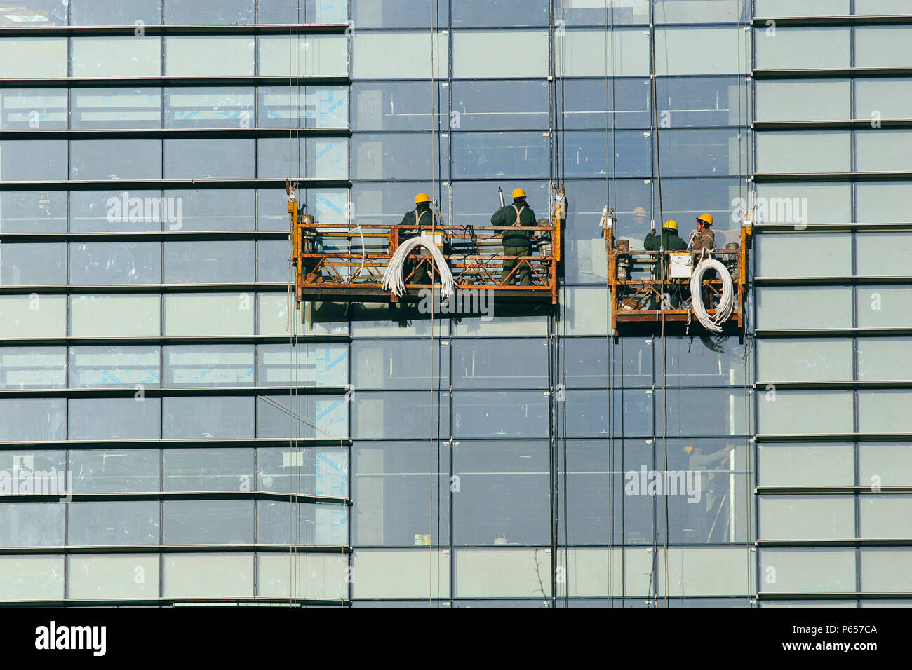 Les travailleurs chinois sur la plate-forme d'accès suspendu pendant les opérations d'entretien de façade. Beijing, Chine. Banque D'Images