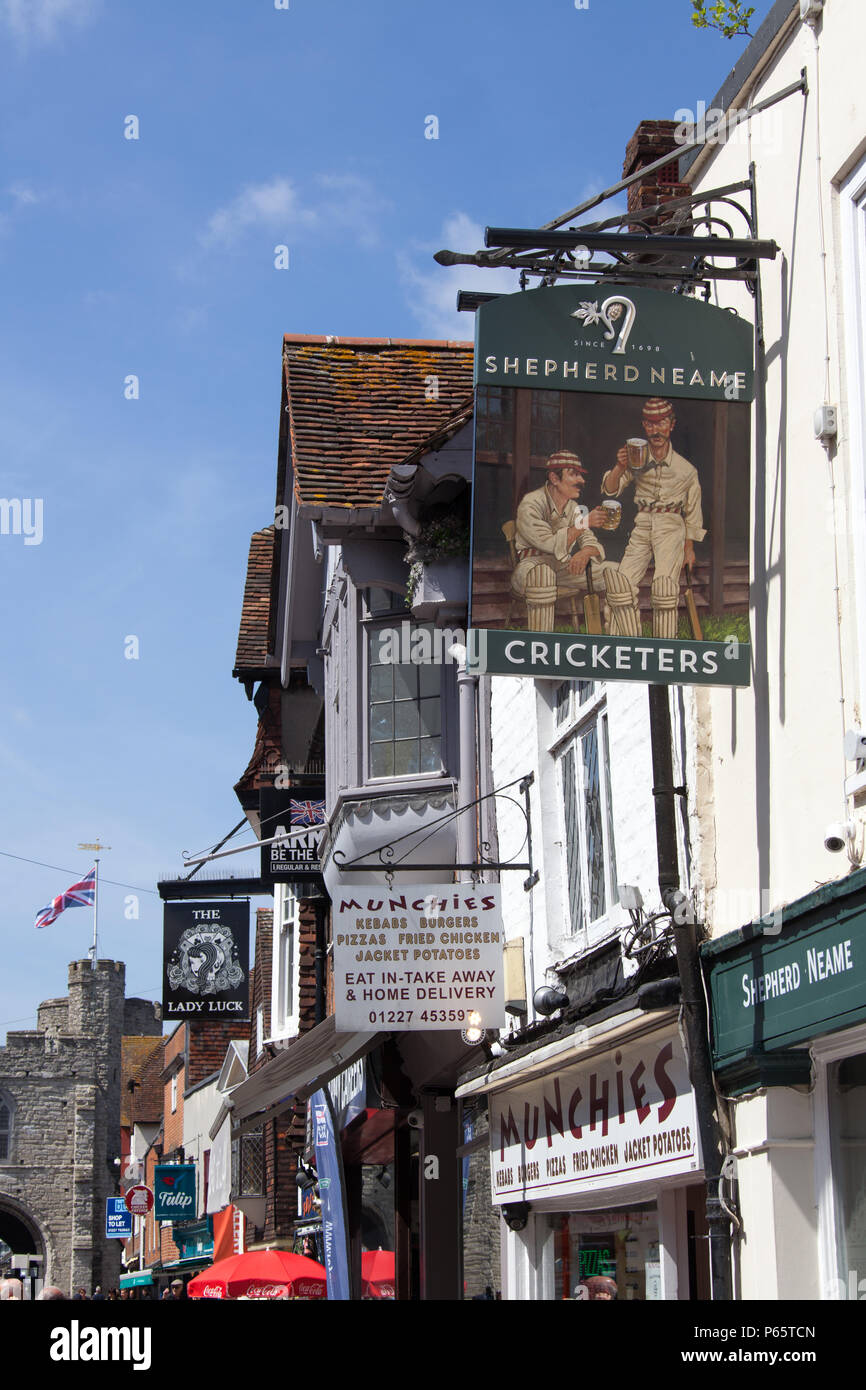Ville de Canterbury, Angleterre. Vue sur la rue pittoresque de pub et de boutiques sur la Canterbury High Street, avec la porte de l'Ouest historique dans l'arrière-plan. Banque D'Images