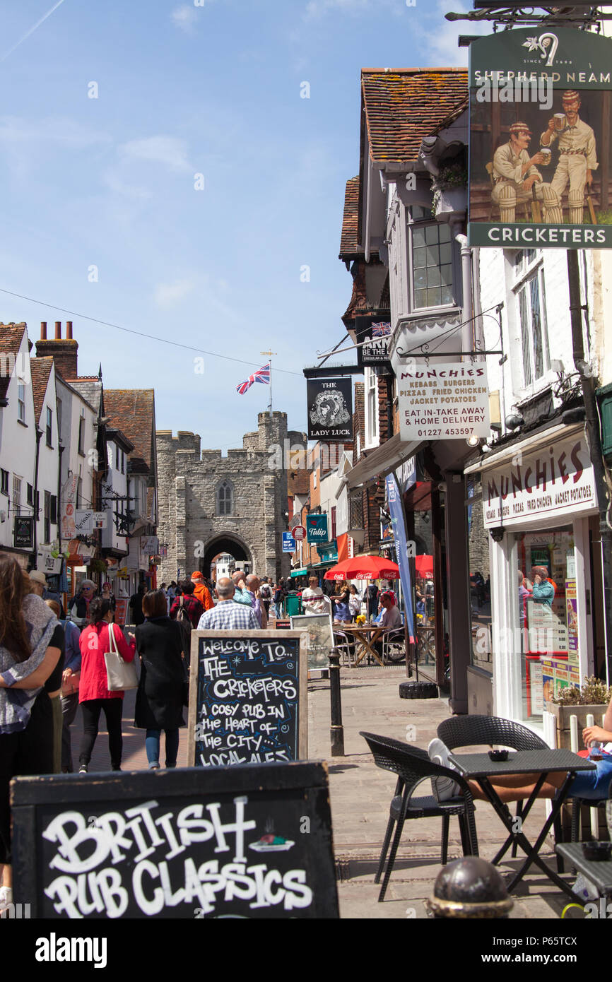 Ville de Canterbury, Angleterre. Vue sur la rue pittoresque de pub et de boutiques sur la Canterbury High Street, avec la porte de l'Ouest historique dans l'arrière-plan. Banque D'Images