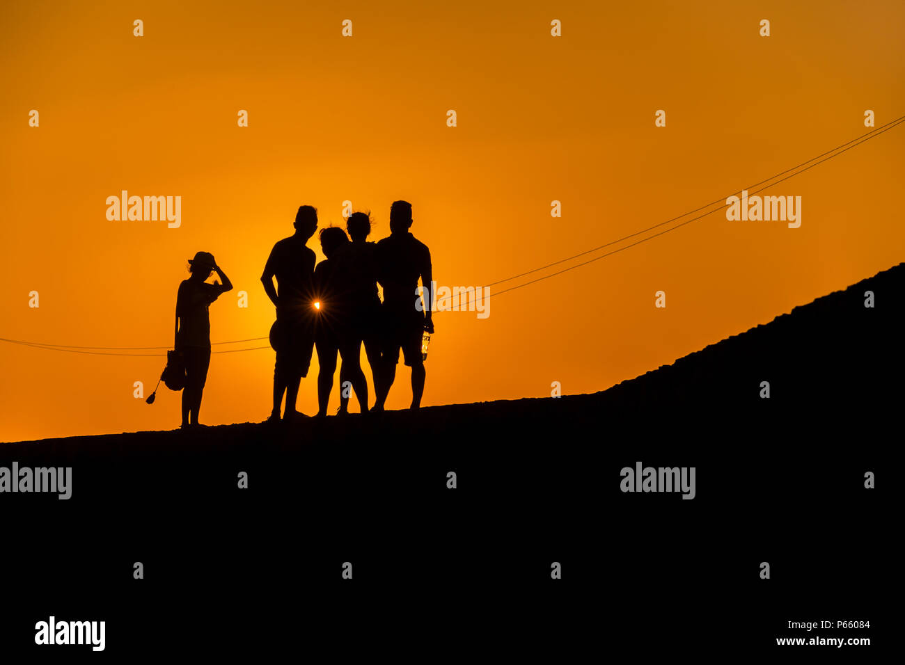 Un groupe de jeunes touristes colombiens regarder le coucher du soleil en marchant sur les murs en pierre entourant la ville fortifiée coloniale à Cartagena, Colombie. Banque D'Images
