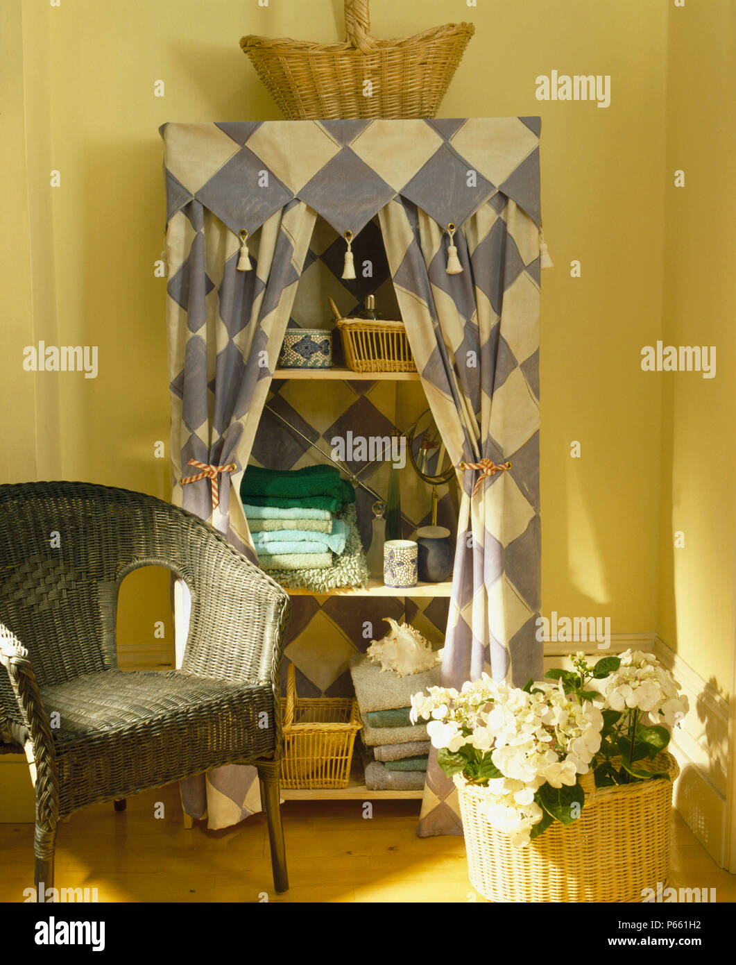 Wicker Chair à côté de l'unité étagère en bois peint à la main avec blanc +bleu motif damier rideaux conseil Banque D'Images