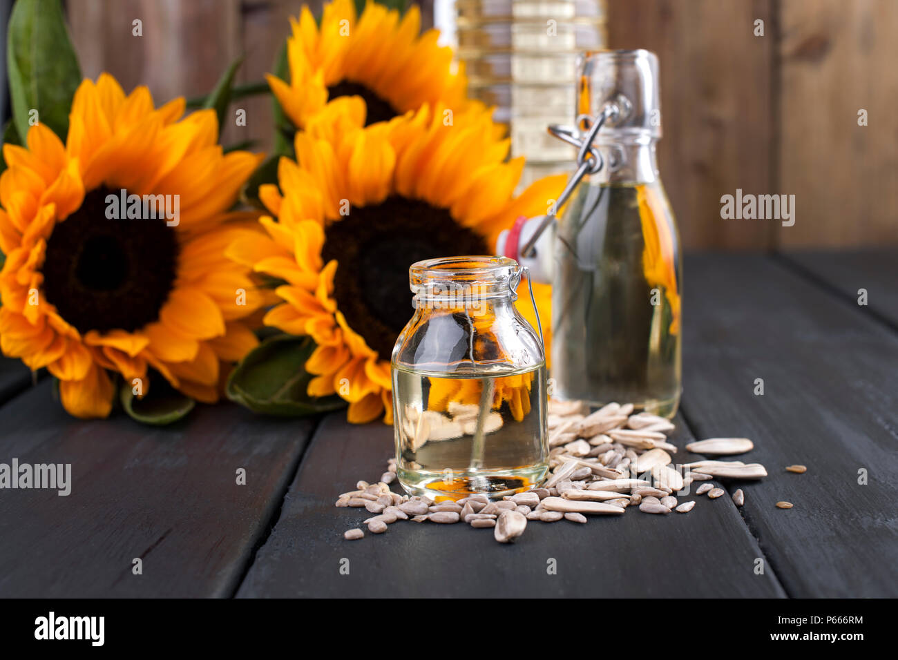 Dodsolnechnoe dans une bouteille d'huile d'une grande et petite, un bouquet de tournesols fleurs, sur un fond de minuscules graines dispersées et. Produit naturel, style rustique. Copy space Banque D'Images