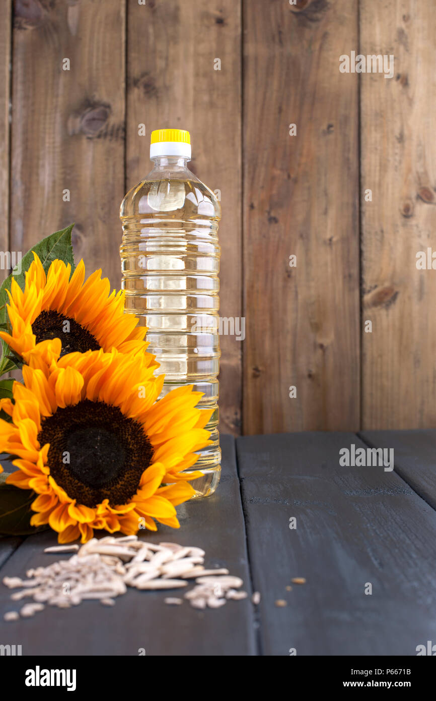 Dodsolnechnoe d'huile dans la bouteille, un bouquet de tournesols fleurs, sur un arrière-plan terned et graines dispersées. Produit naturel, style rustique. Copy space Banque D'Images