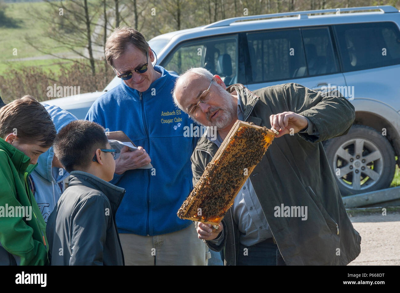Lors de la Journée de la Terre à Oberdachstetten Range Training Area, en Allemagne, le 20 avril 2016, un apiculteur montre aux élèves une ruche pour illustrer comment les abeilles indiquent la pollution environnementale. L'événement promeut l'éducation écologique, la conservation, la biodiversité, la durabilité, la protection des écosystèmes, sensibilisation à l'environnement et pratiques visant à maintenir des habitats naturels propres pour des écosystèmes sains et la santé planétaire à long terme. Banque D'Images