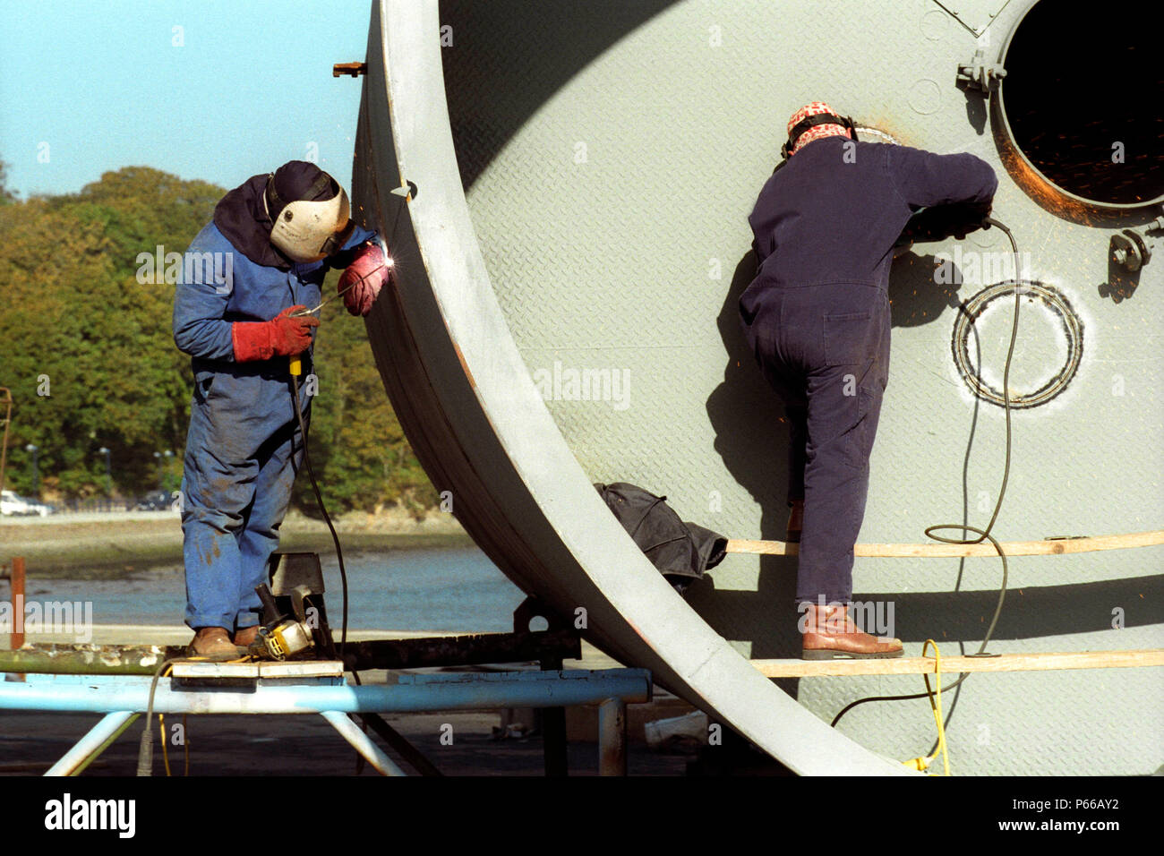 Soudeur et Grinder travaille sur un grand réservoir pour l'industrie pétrolière, Milford Haven, Pembrokeshire, Pays de Galles de l'Ouest Banque D'Images