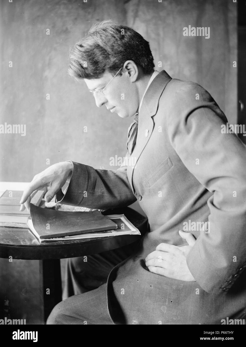 Clarence White Sr par le photographe Gertrude Käsebier, 1852-1934. Clarence White, Sr. dans un tailleur, assis, tourné à gauche, sur le point d'ouvrir un livre. Daté entre 1897 et 1910 Banque D'Images