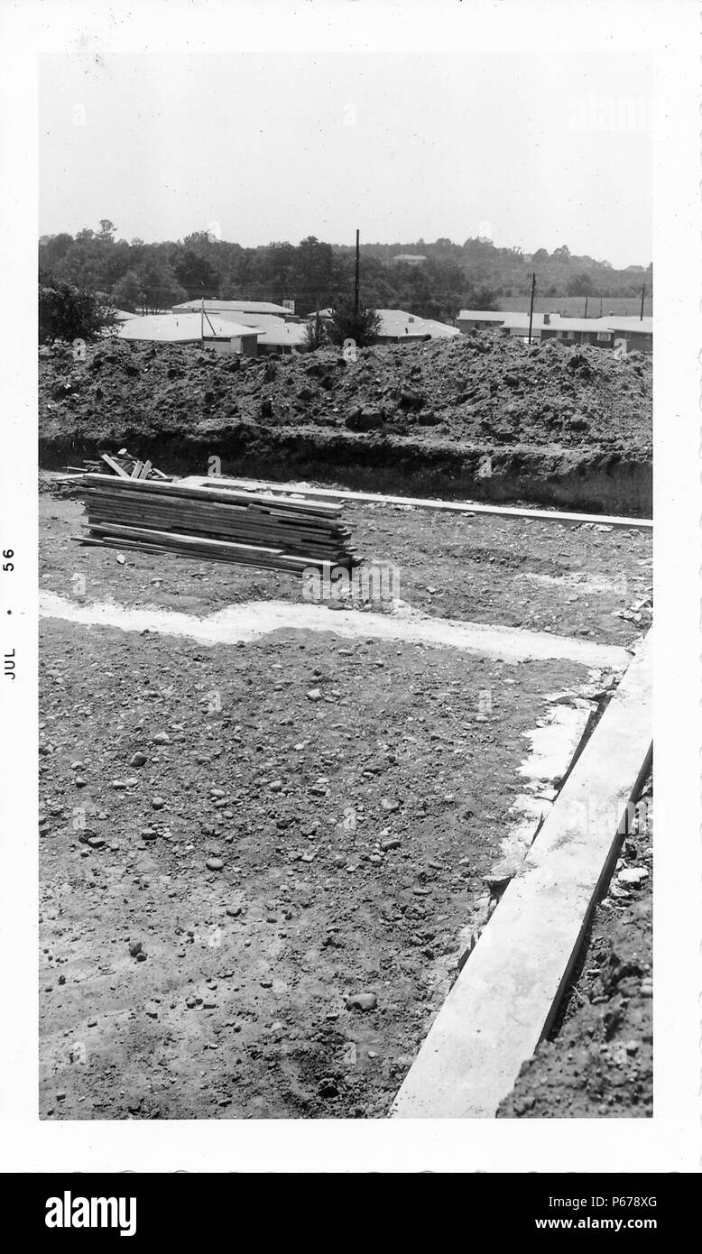 Photographie noir et blanc, montrant un site de construction, avec l'ébauche d'une fondation en béton, la saleté, et des longueurs de bois, avec les toits de maisons en arrière-plan, probablement photographié dans l'Ohio, Juillet, 1956. () Banque D'Images