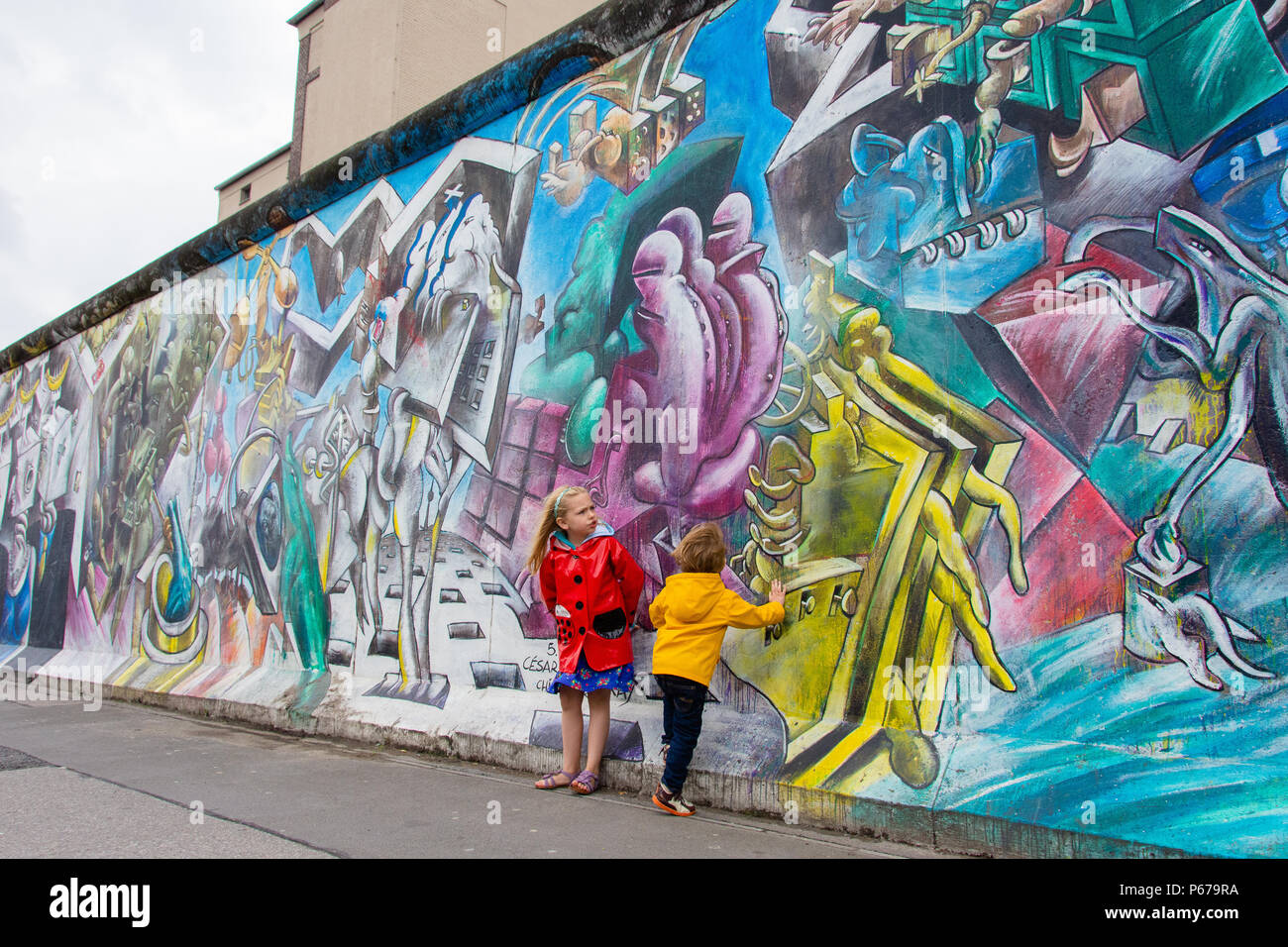 30 juin 2017 : Les enfants se tient en dehors de la peinture et Graffiti sur l'Eastside Gallery de Berlin, Allemagne. Banque D'Images