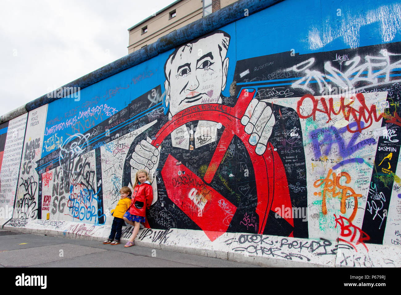 30 juin 2017 : Les enfants se tient en dehors de la peinture et Graffiti sur l'Eastside Gallery de Berlin, Allemagne. Banque D'Images