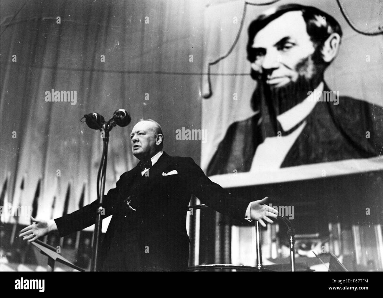 Photo de Winston Churchill (1874-1965), parlant à l'Albert Hall devant une grande photo d'Abraham Lincoln (1809-1865). Datée 1944 Banque D'Images