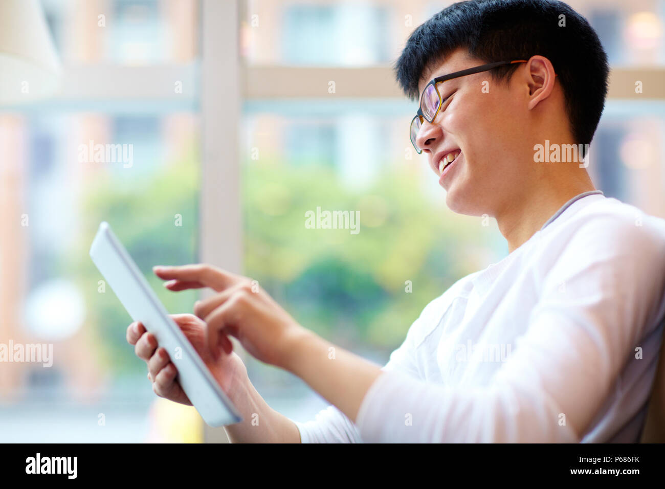 Jeune homme chinois à l'aide de tablet in cafe Banque D'Images