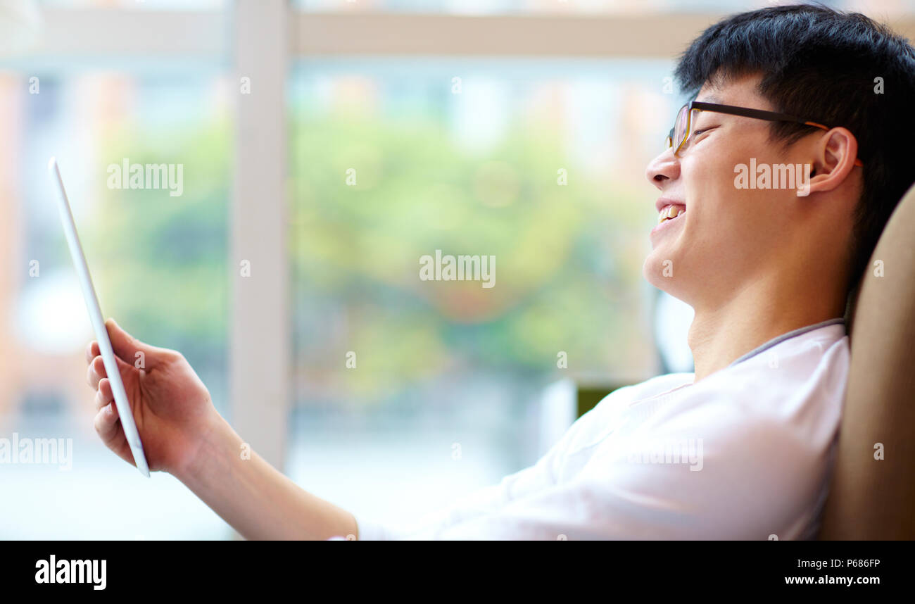 Jeune homme chinois à l'aide de tablet in cafe Banque D'Images