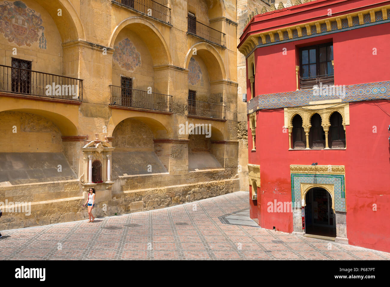 Une jeune femme espagnole marche seule devant le mur mauresque arcadé de la cathédrale-Mosquée (la Mezquita) sur la Plaza del Triunfo, Cordoue, Andalousie. Banque D'Images
