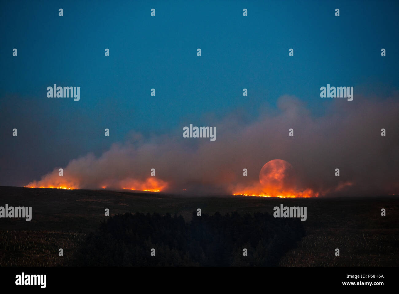 La colline d'hiver, le Grand Manchester, UK. 28 Jun, 2018. La lune se lève sur un feu d'herbe sur les terrains marécageux de la colline d'hiver, près de Bolton dans le Grand Manchester. Crédit : Jason Smalley Photography/Alamy Live News Banque D'Images