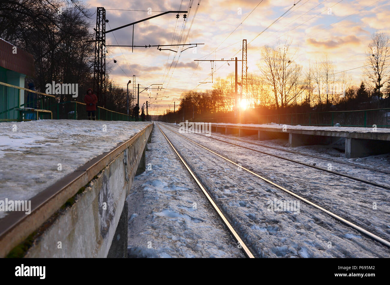 Photo de lumineux et beau coucher de soleil sur un ciel nuageux en saison froide d'hiver. Voie de chemin de fer avec des plates-formes pour les trains en attente de transmission de puissance et de lin Banque D'Images