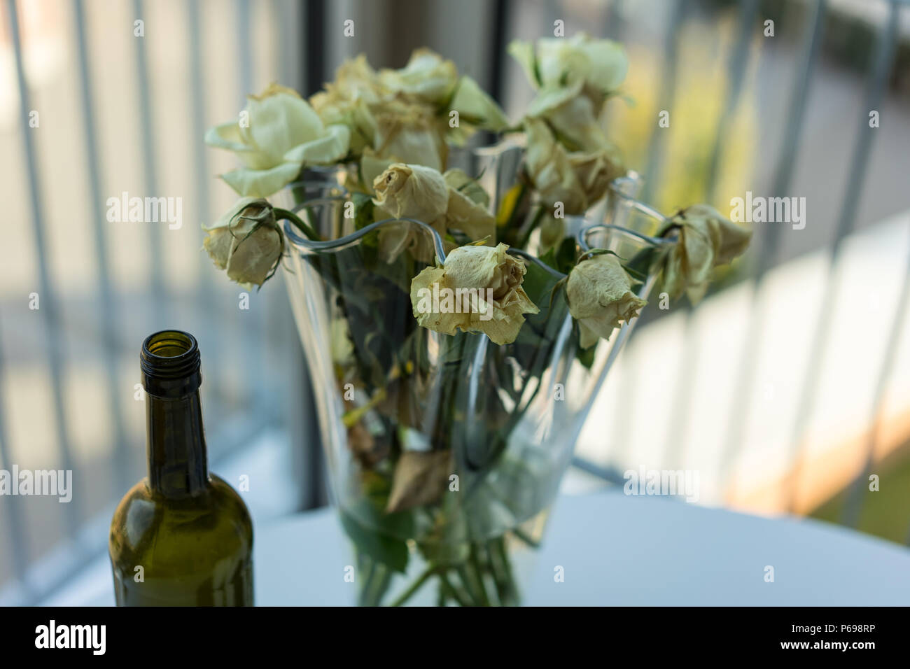 Roses jaunes flétries et bouteille de vin sur la table Banque D'Images