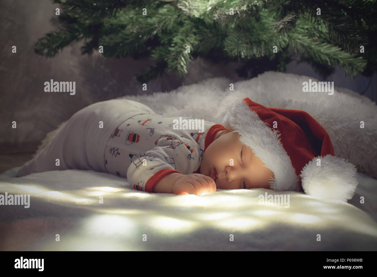 Bébé nouveau-né garçon dormir sous arbre de Noël sur la masse d'éclairage blanc Banque D'Images