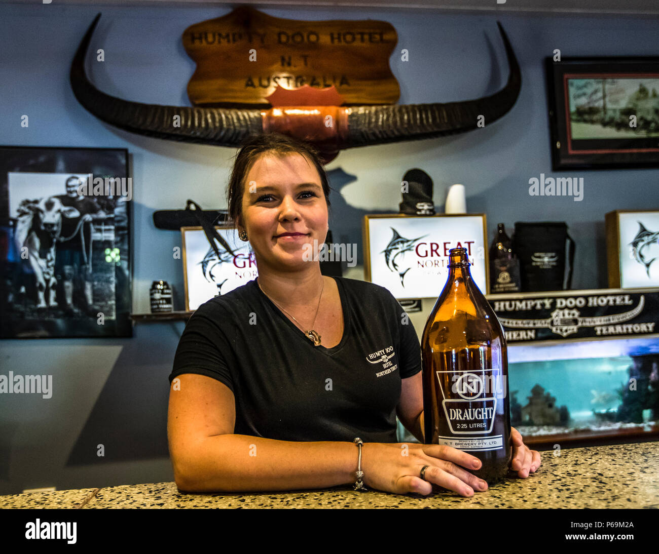 Un employé présente une bouteille de 2,25 litre connue sous le nom de « Darwin Stubby » au bar du Humpty Doo Hotel, dans le Territoire du Nord, en Australie. La bouteille surdimensionnée a été introduite en 1958 pour des raisons d'expédition et arrêtée en 2015 ; elle est devenue célèbre grâce à des concours de consommation avec le taureau Brahman Norman, qui en a une fois vidée une en 47 secondes. Banque D'Images
