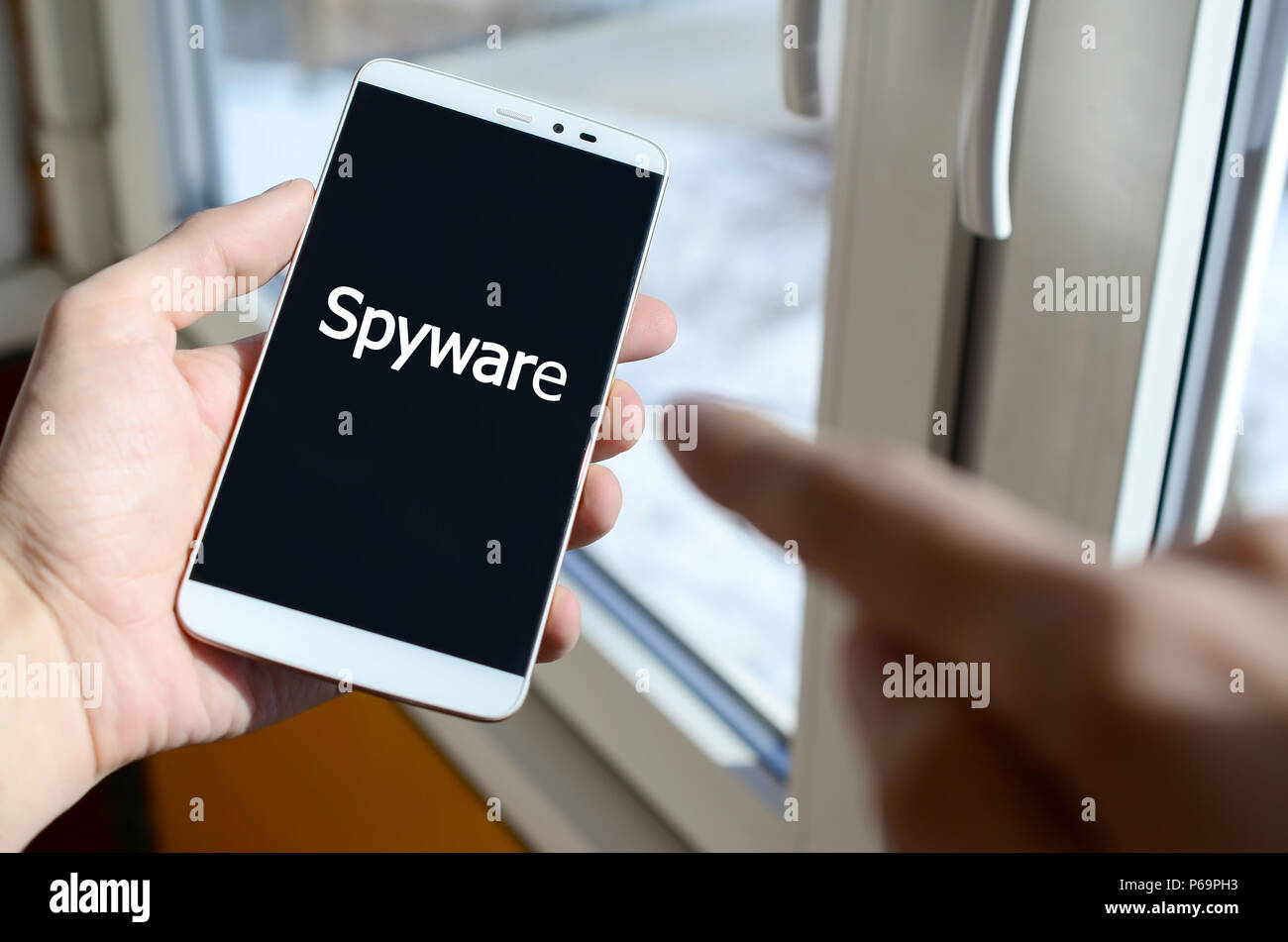 Une personne voit une inscription blanche sur un écran de smartphone noir qui tient dans sa main. Les logiciels espions . Banque D'Images