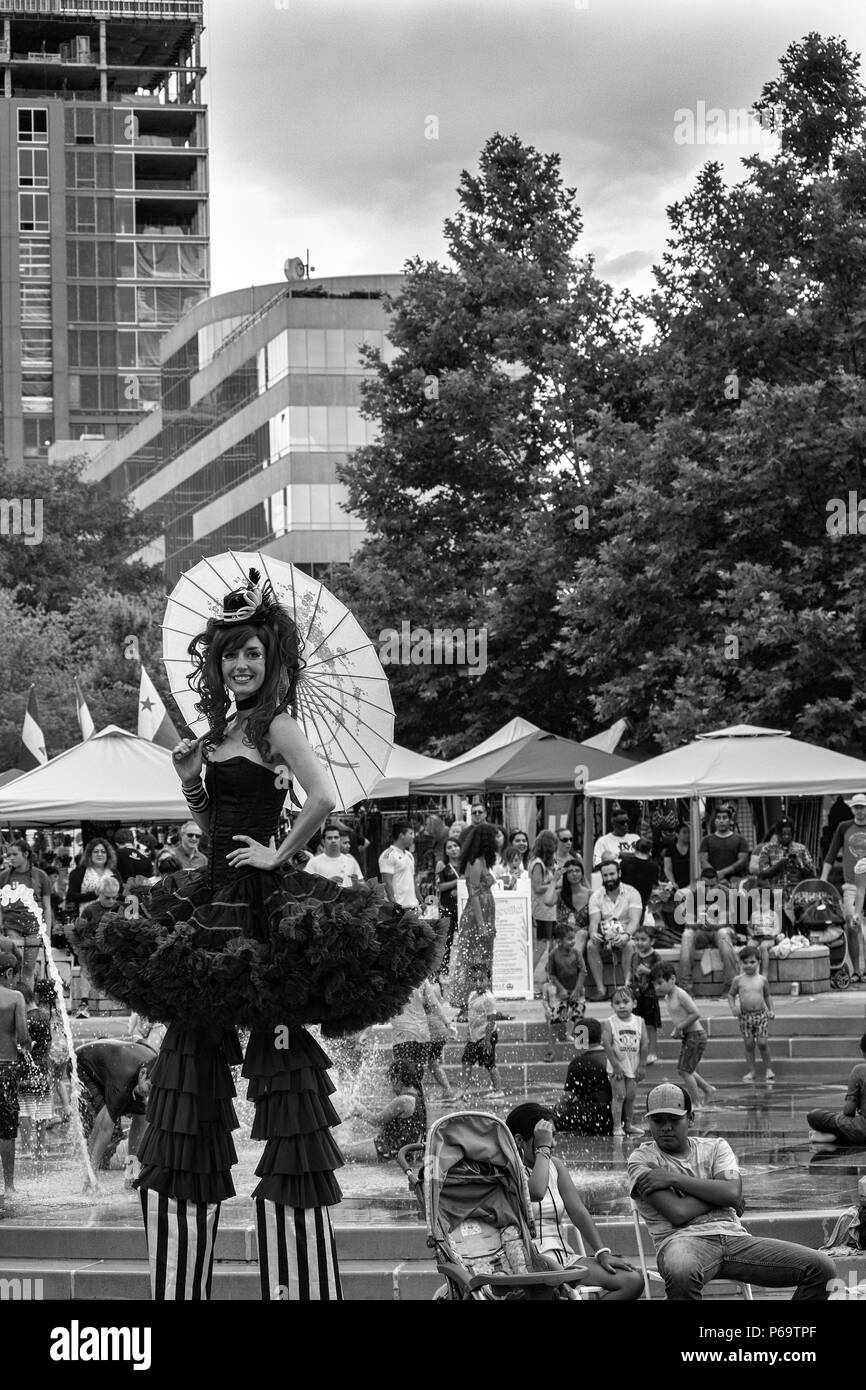 Une femme se dresse sur pilotis avec un parasol sur la Hola Carolina festival, avec des arbres et du centre-ville de Asheville, NC, USA en arrière-plan. Banque D'Images