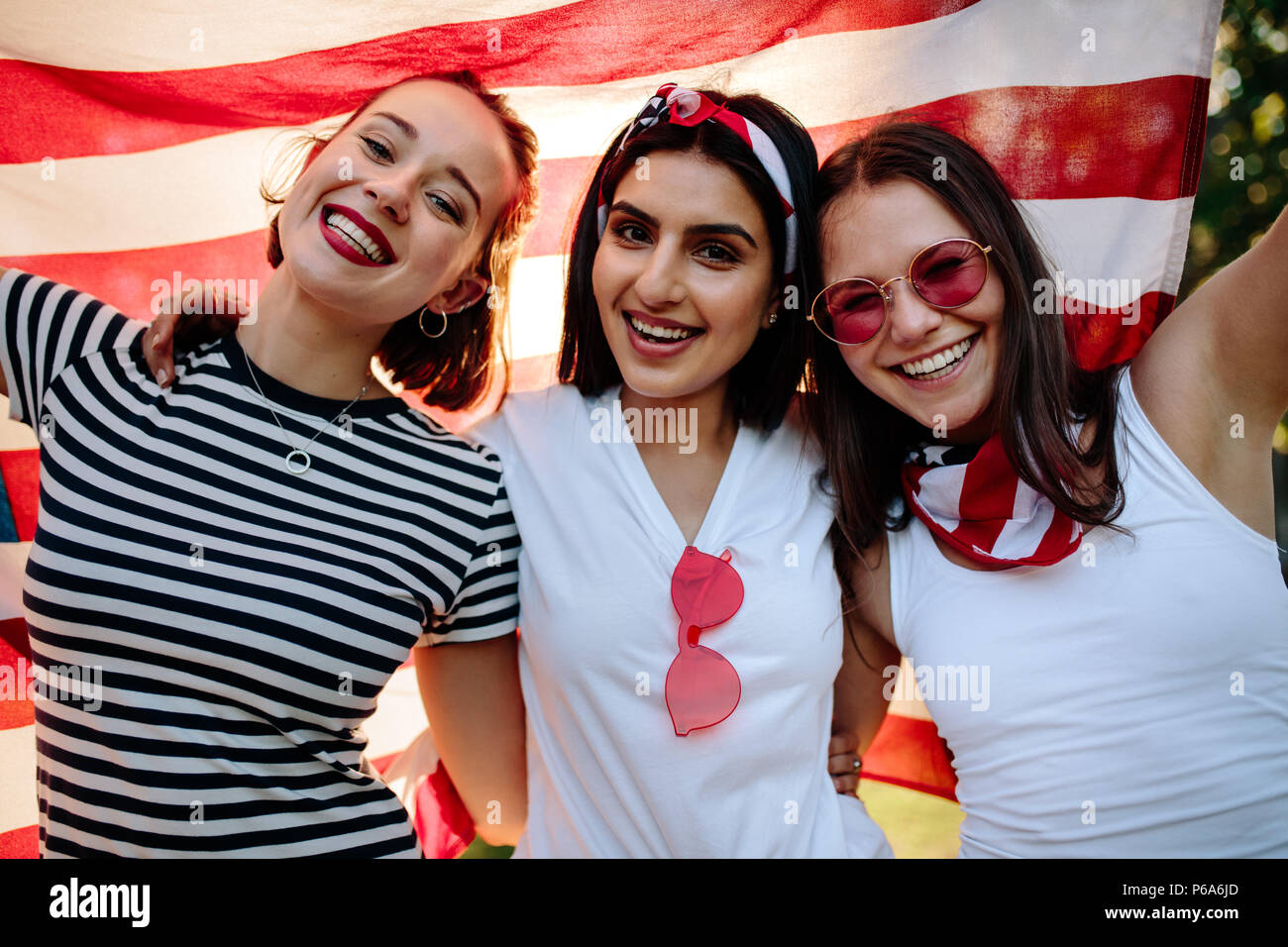 Trois femmes friends smiling avec le drapeau américain. Les femmes amis avec USA flag smiling at camera. Banque D'Images