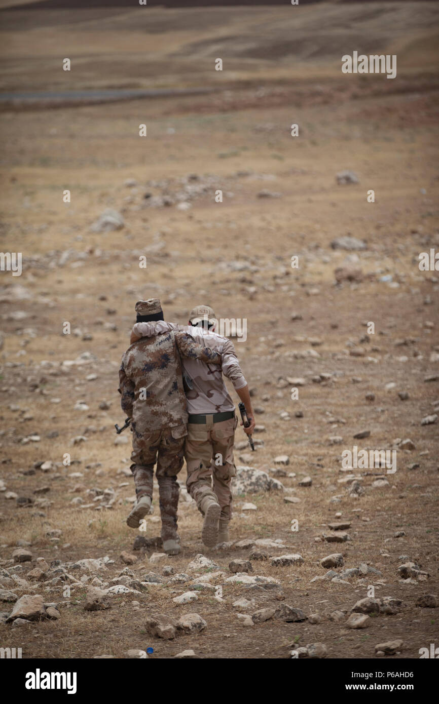 Un soldat de l'Unité de Protection de la Plaine de Ninive aide un autre soldat agissant comme un combat au flanc de la montagne au cours d'une formation, ils réagissent au contact de l'exercice dans leur centre de formation à la province de Ninive, le 18 mai 2016. La NPPU sont un petit groupe de combattants qui ont uni leurs efforts pour protéger leurs populations dans la lutte contre l'Etat islamique d'Irak et du Levant. La formation axée sur l'Équipe spéciale mixte - fonctionnement inhérentes à l'ensemble de la mission de résoudre renforcer les capacités des partenaires et d'accroître la capacité militaire des forces locales combats ISIL. (U.S. Photo par le personnel de l'armée Banque D'Images