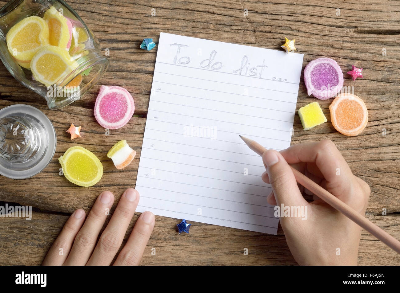 Main femme écrire liste des tâches sur table en bois avec des bonbons en gelée Banque D'Images