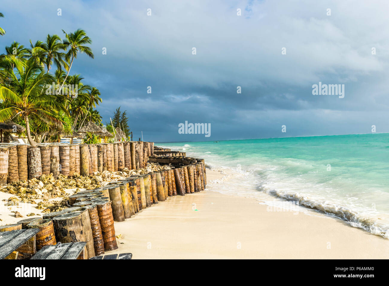 L'eau turquoise, plage de sable fin avec palmiers et ciel orageux Banque D'Images