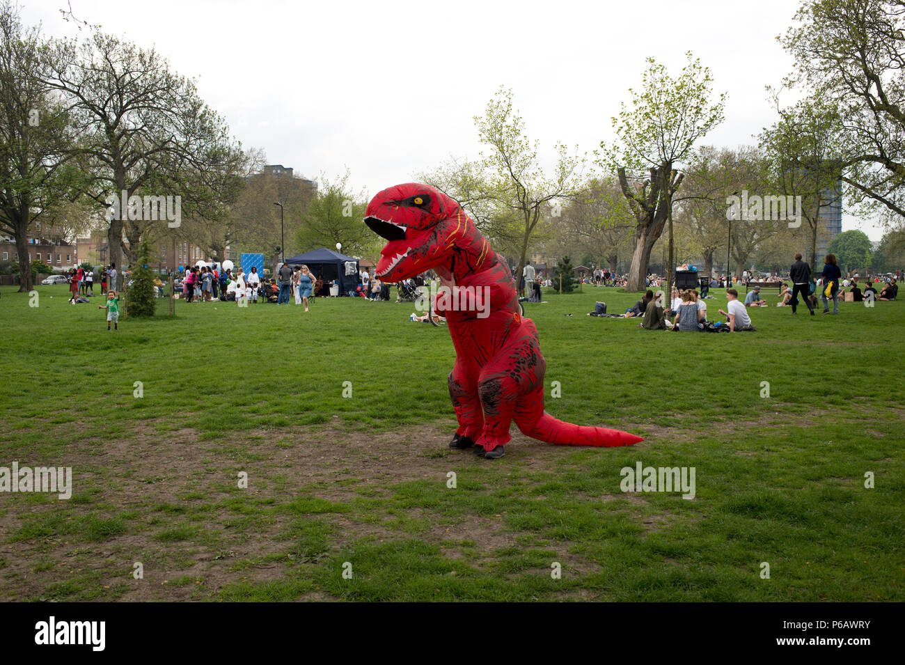 Londres. Hackney. Champs de Londres. Un homme sur son stag célébration est habillé comme un dinosaure rouge. Banque D'Images