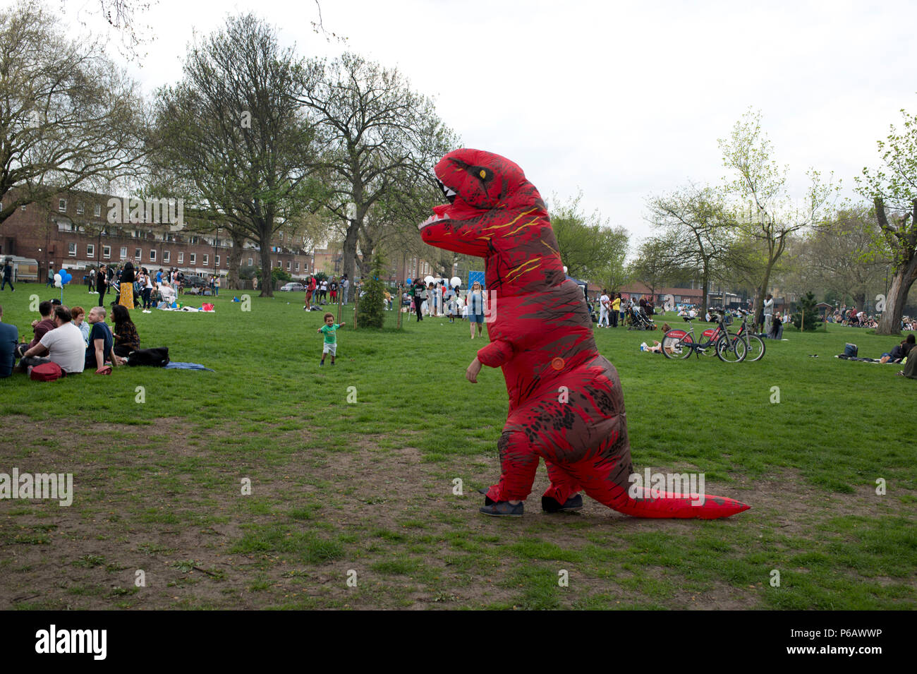 Londres. Hackney. Champs de Londres. Un homme sur son stag célébration est habillé comme un dinosaure rouge. Banque D'Images