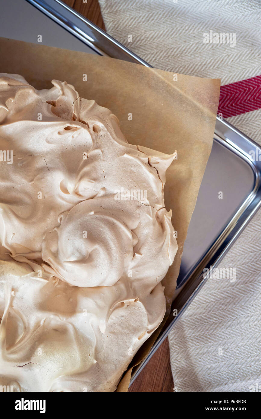 La cuisine de base de meringue pour une Pavlova dessert. La meringue fraîche, avec du haut d'or, sur le papier sulfurisé et une plaque de cuisson en acier inoxydable Overhea Banque D'Images