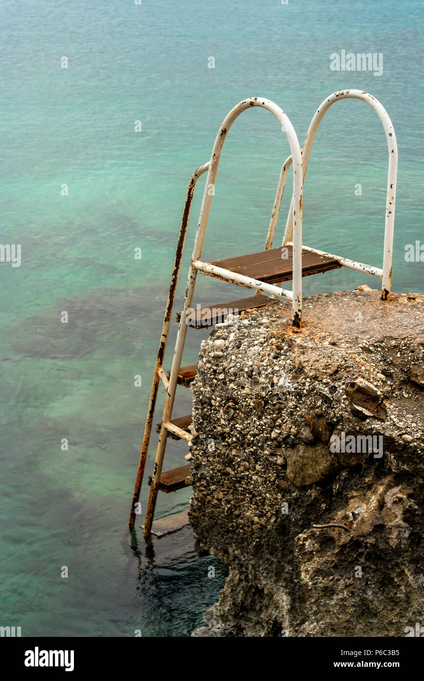 Un metal set une échelle installée dans aux rochers sur la rive à l'aide des baigneurs dans et hors de la mer Méditerranée. Banque D'Images