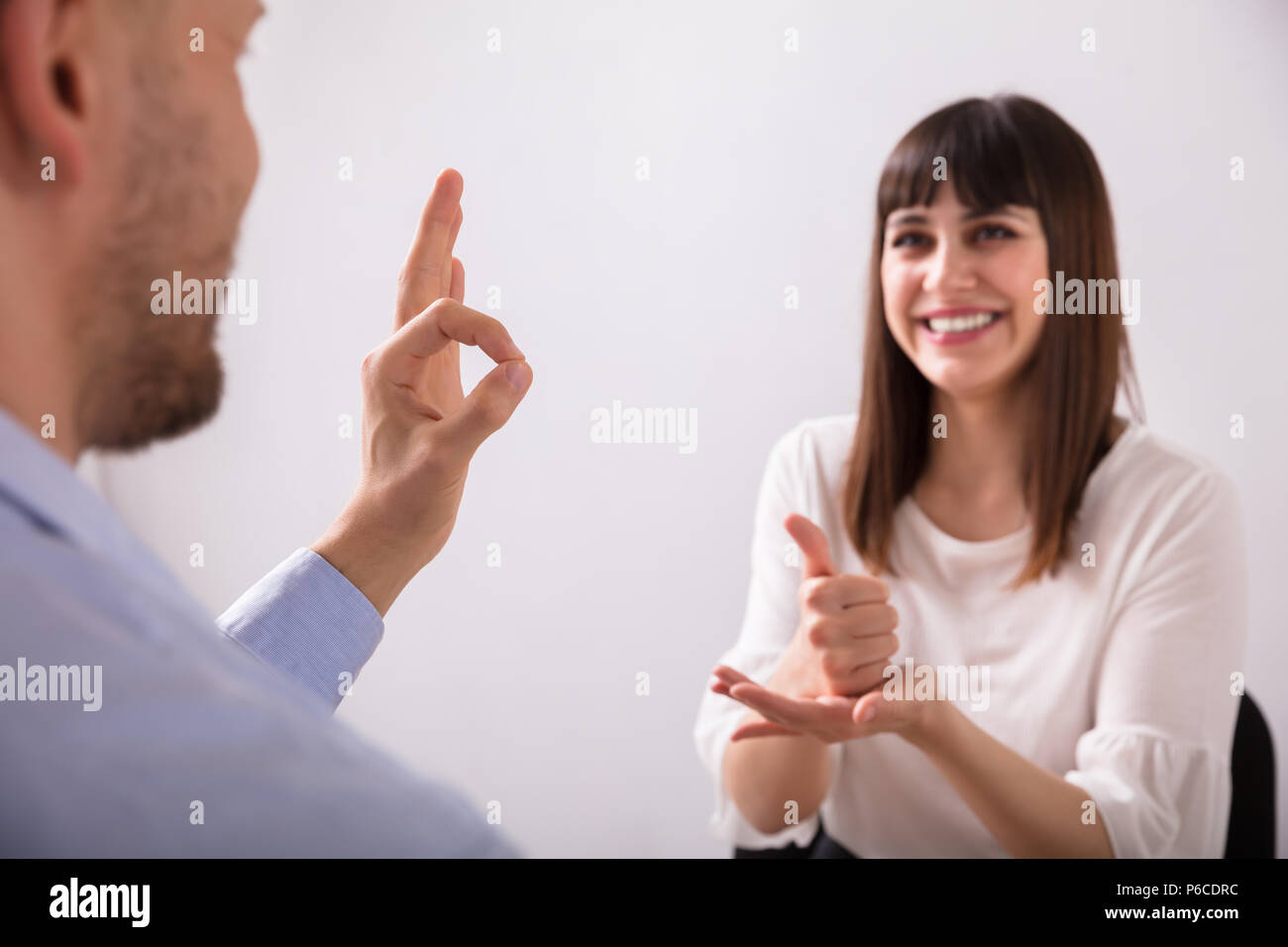 Souriante jeune femme et l'homme parle avec la langue des signes sur fond blanc Banque D'Images