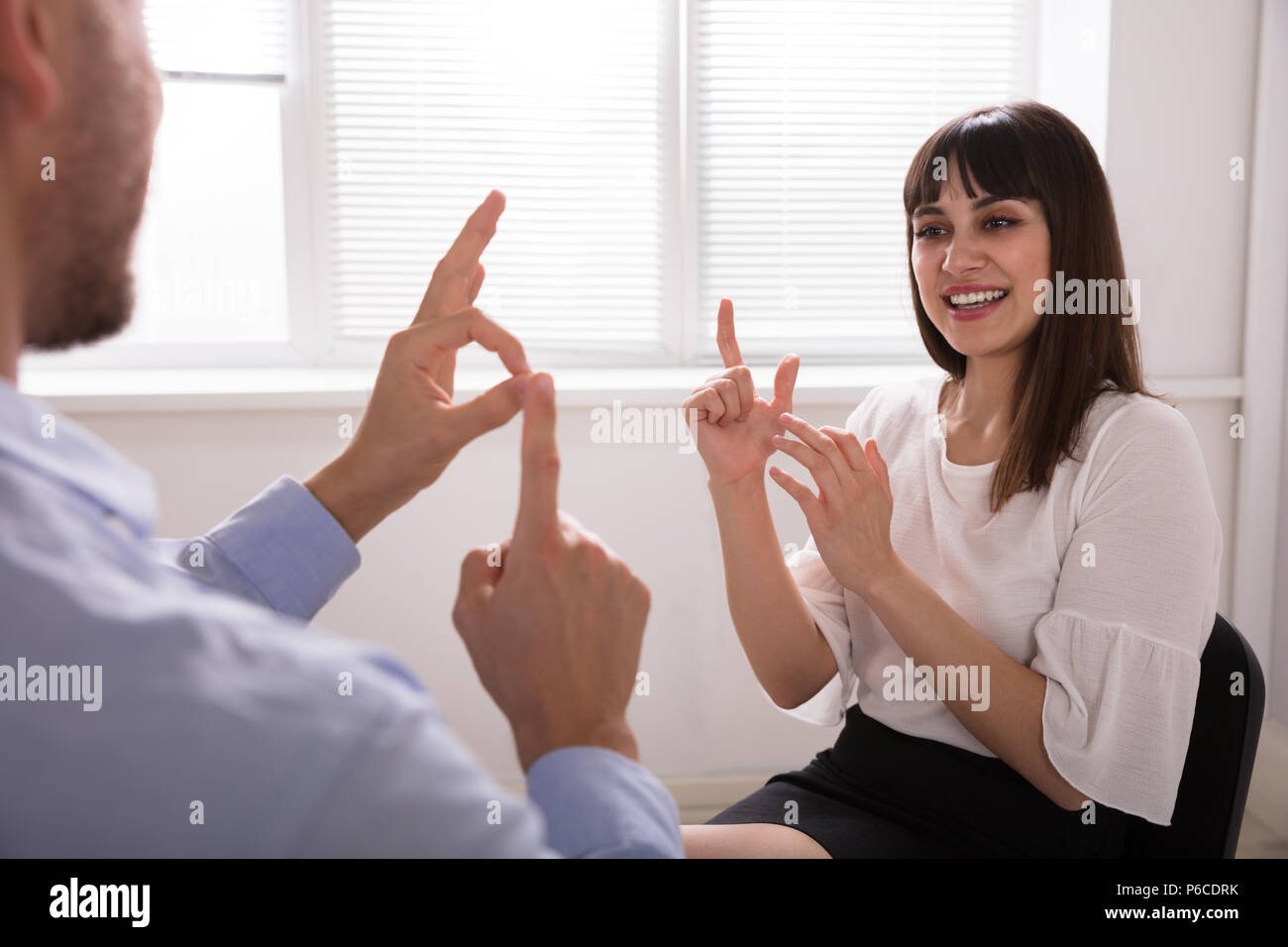 Souriante jeune femme et l'homme parle avec la langue des signes sur fond blanc Banque D'Images