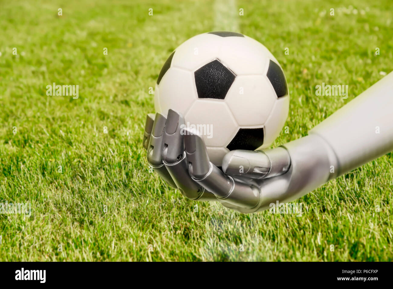 Le bras d'un robot permet de rejoindre un football. Le terrain de soccer avec la machine. Le bras du robot est en face d'un terrain de soccer. Banque D'Images