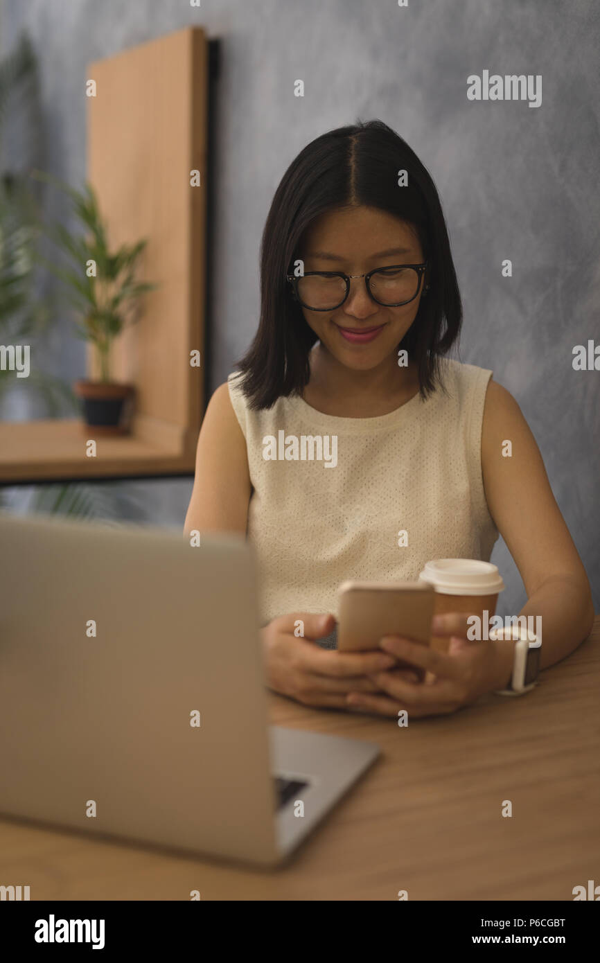 Pregnant businesswoman using mobile phone at desk Banque D'Images