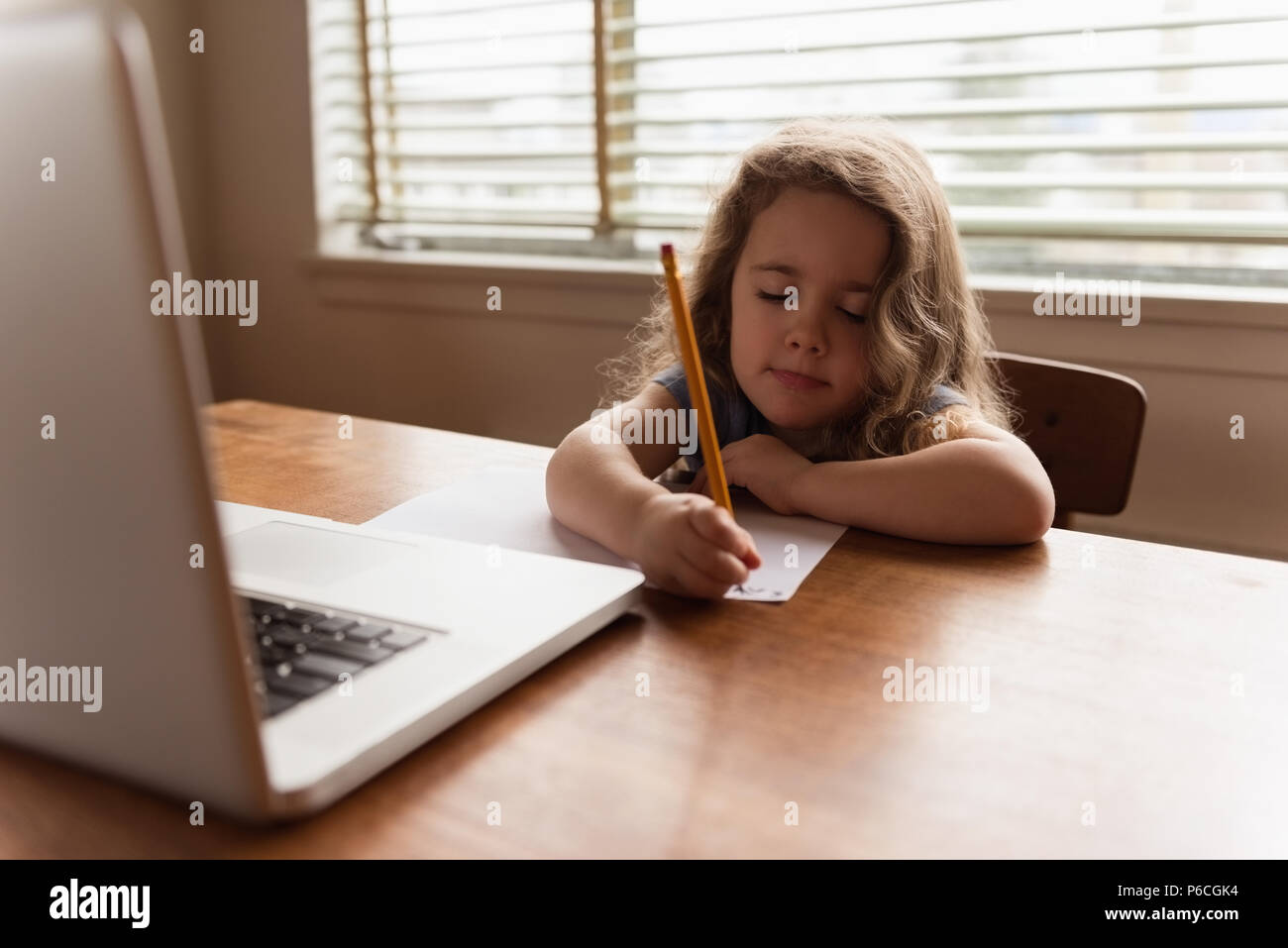 Girl écrit avec un crayon sur une feuille de papier. Banque D'Images