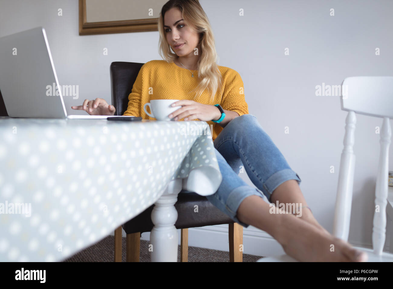 Femme à l'aide de l'ordinateur portable sur une table à manger Banque D'Images