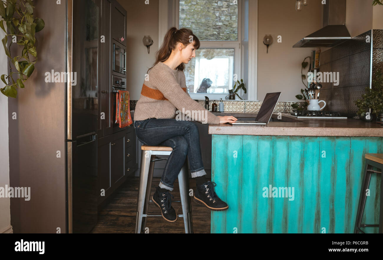 Woman using laptop in kitchen Banque D'Images