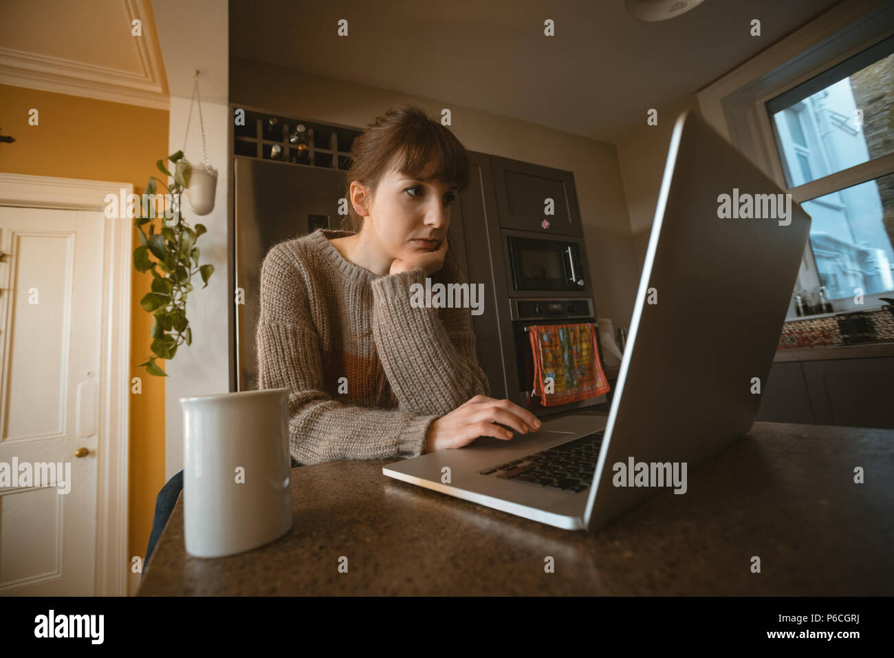 Woman using laptop in kitchen Banque D'Images