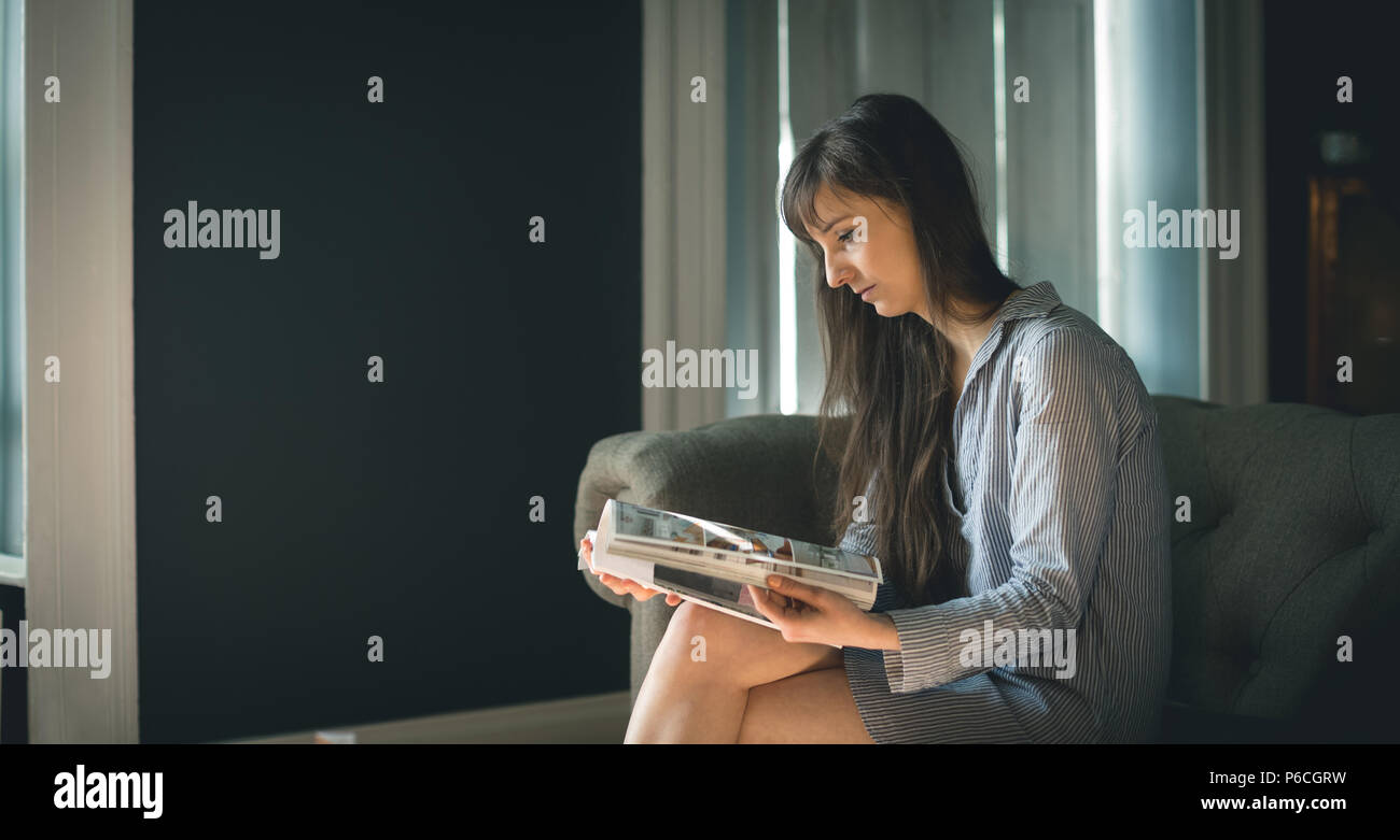 Woman Reading magazine dans la salle de séjour Banque D'Images