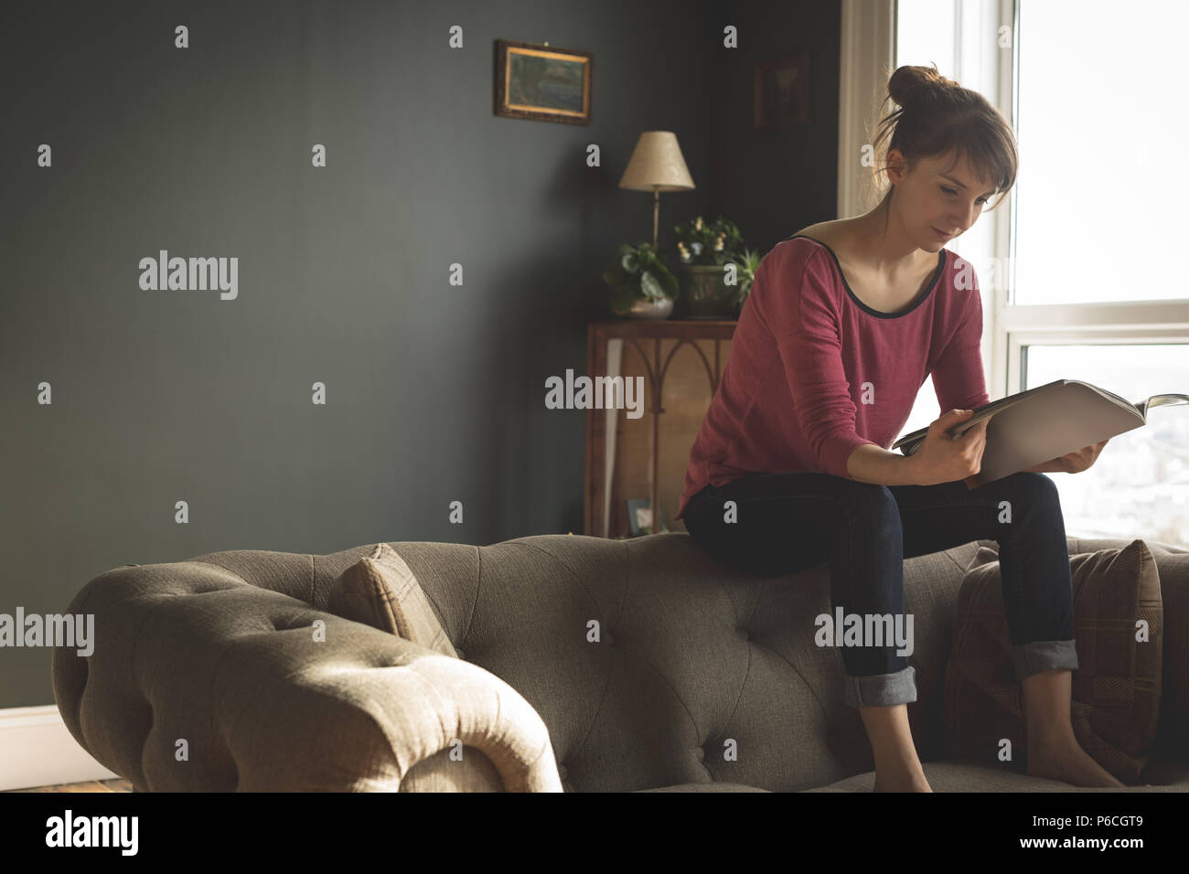 Woman Reading book in living room Banque D'Images
