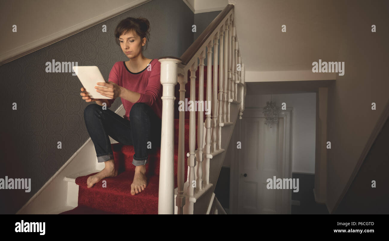Woman using digital tablet on staircase Banque D'Images