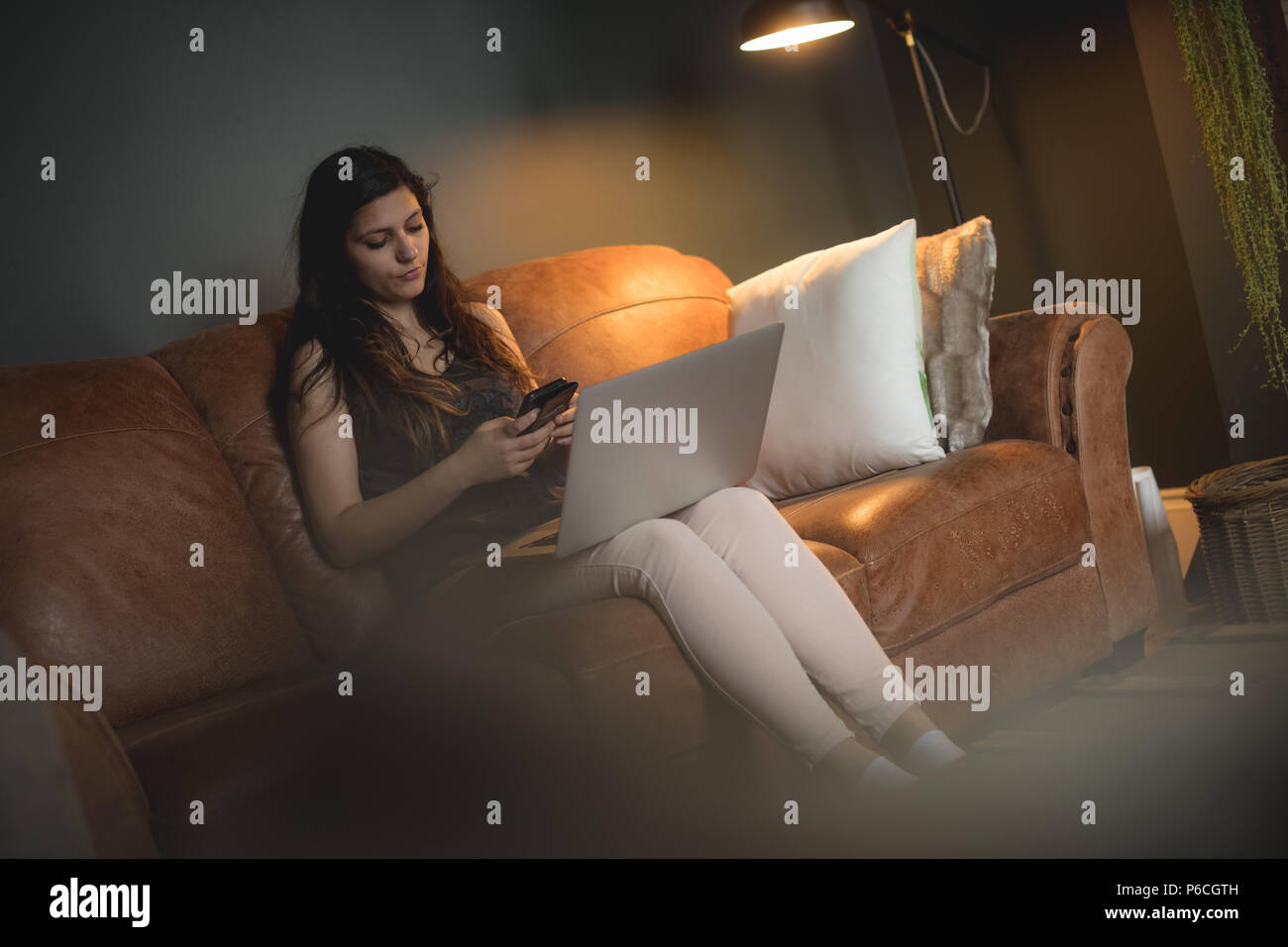 Woman using mobile phone at home Banque D'Images