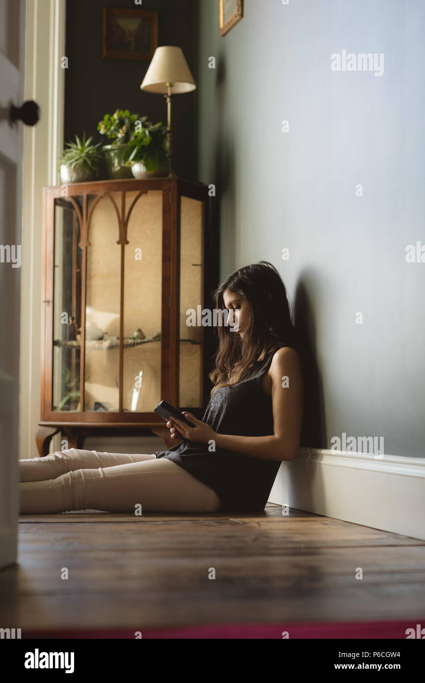 Woman using mobile phone at home Banque D'Images