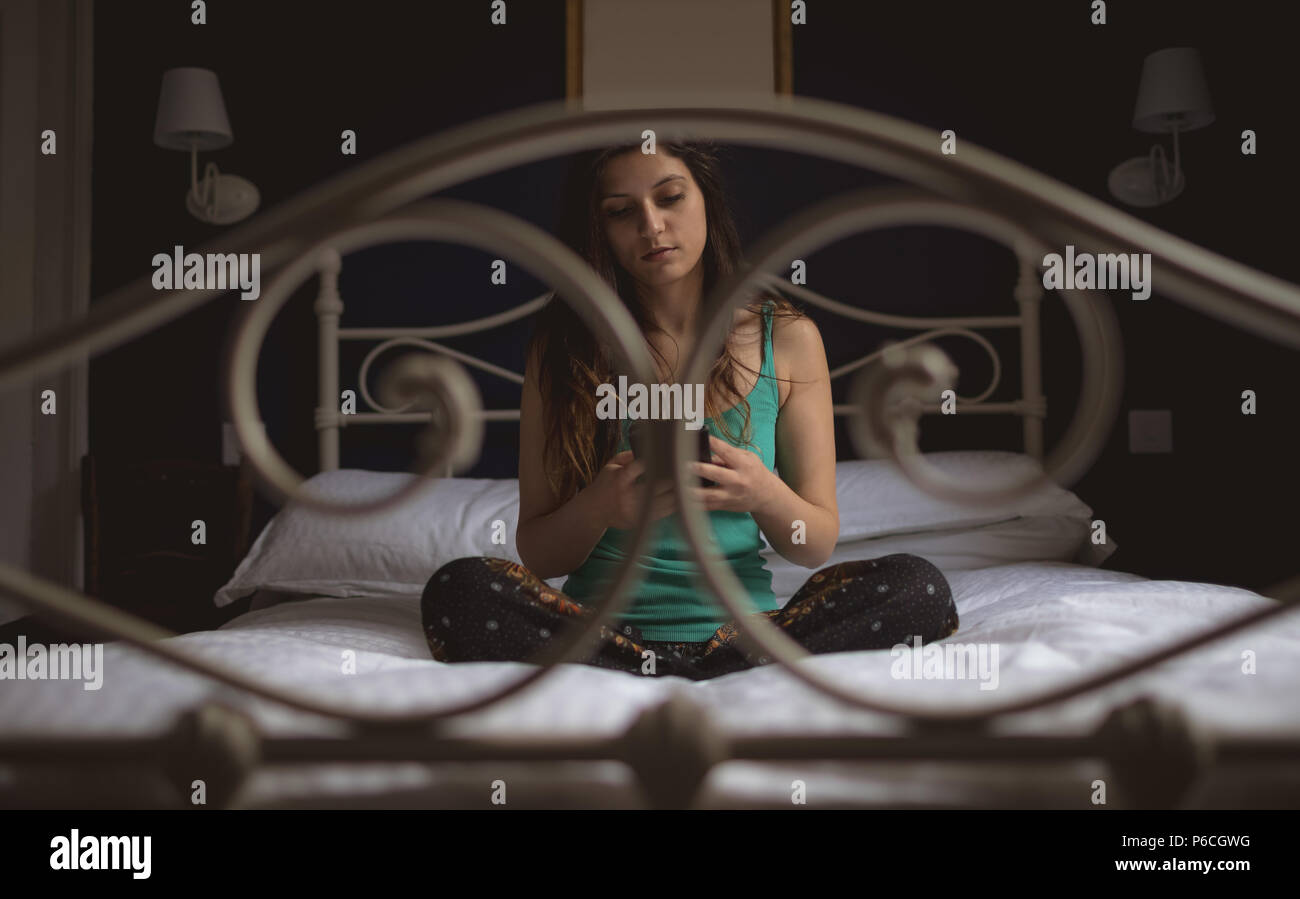 Woman using mobile phone on lit dans la chambre Banque D'Images