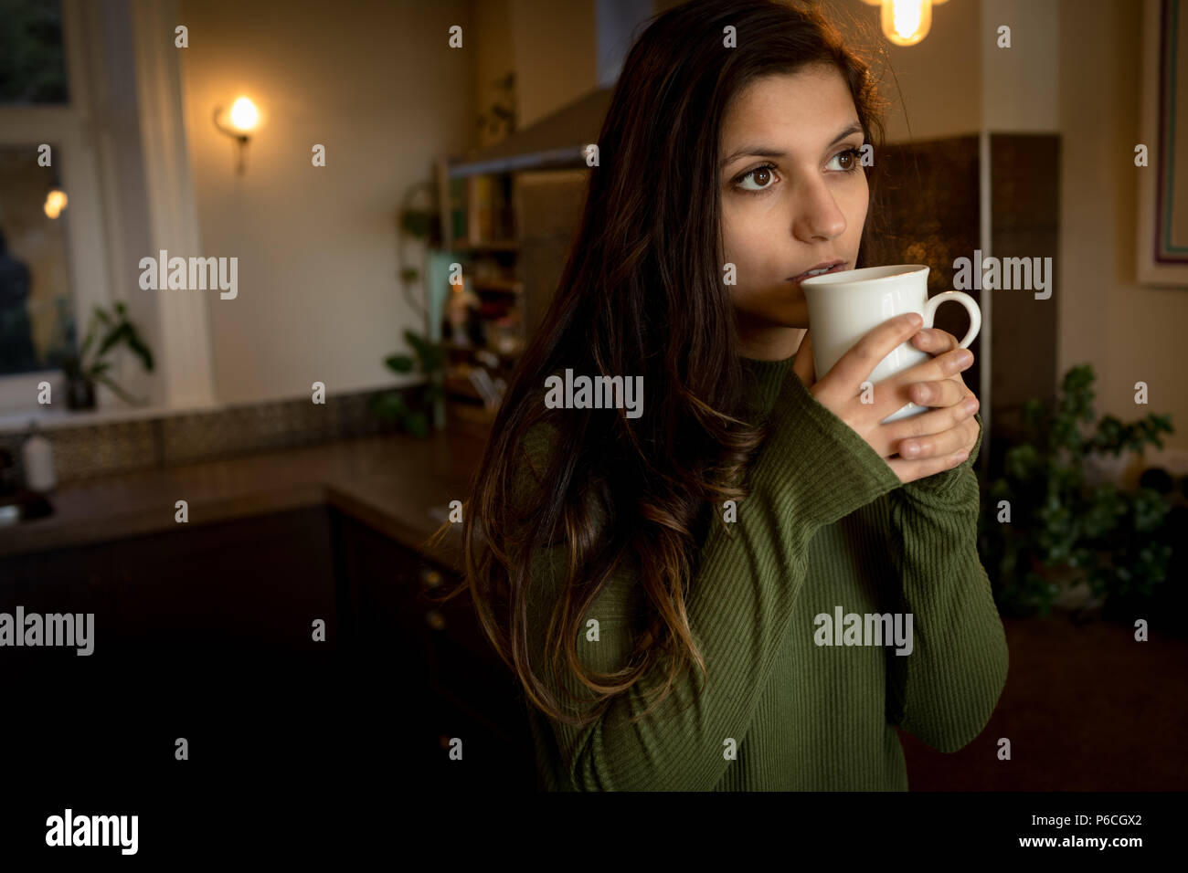 Thoughtful woman having coffee in living room Banque D'Images