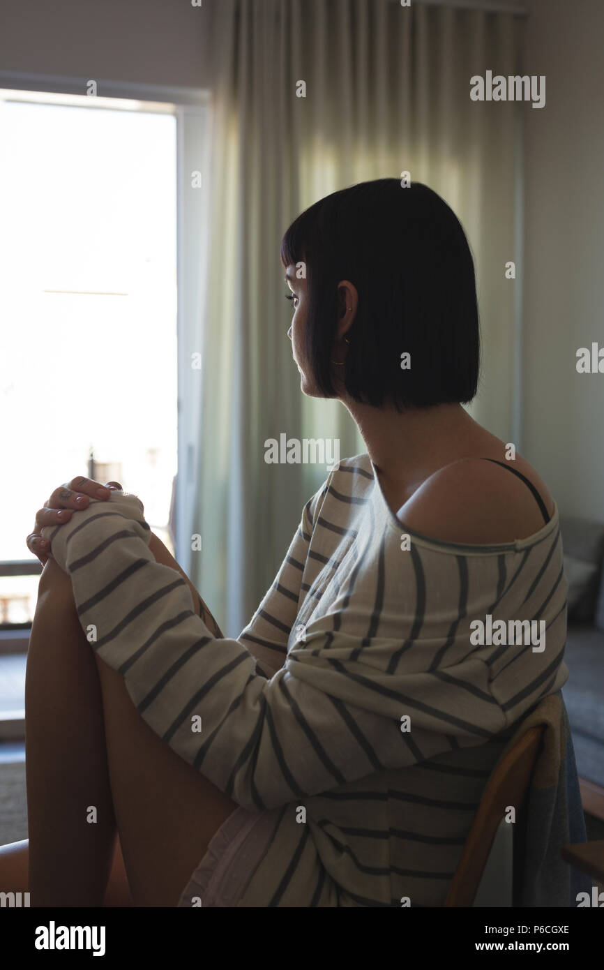 Worried woman sitting on sofa in living room Banque D'Images