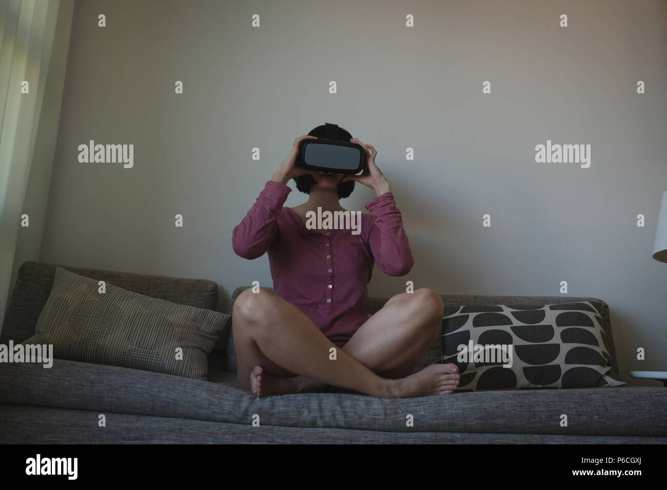 Femme à l'aide de casque de réalité virtuelle dans la salle de séjour Banque D'Images