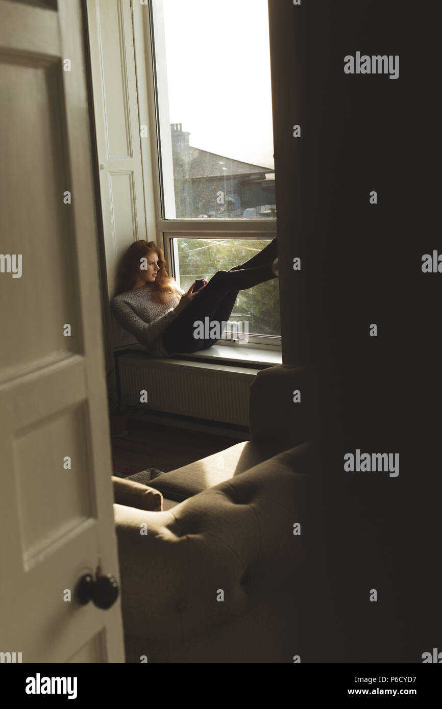 Woman using mobile phone at home Banque D'Images